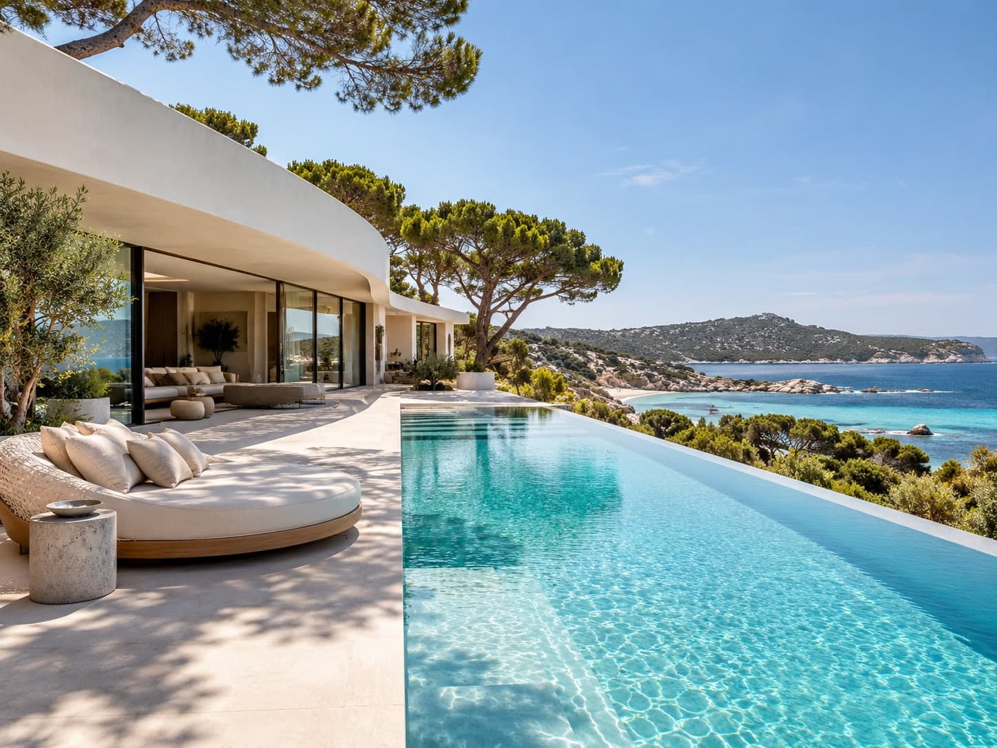 Villa contemporaine aux courbes blanches, piscine à débordement et eau turquoise sous les pins
