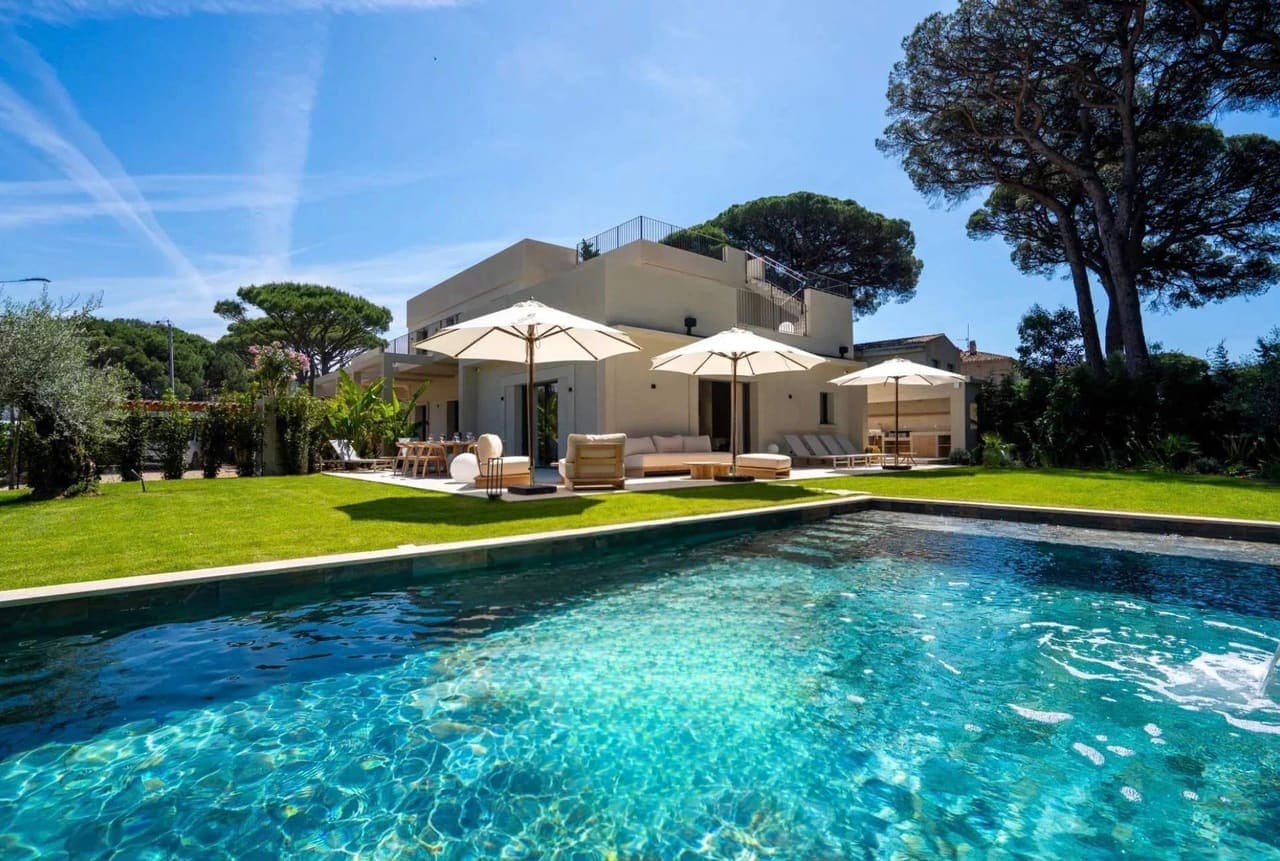 Villa des plages et sa piscine entourée de pelouse et de pins